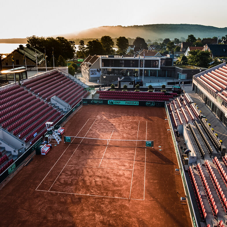 Tennisbana i båstad med solnedgång och tom läktare.