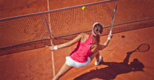 Kvinna som spelar tennis på rött grus